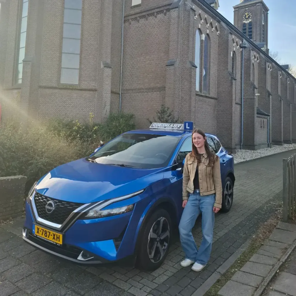 Geslaagde leerling Freya bij de blauwe lesauto van Autorijschool Goedhart