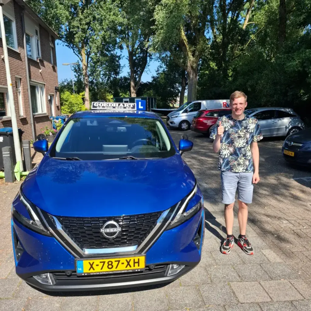 Geslaagde leerling Giel bij de blauwe lesauto van Autorijschool Goedhart
