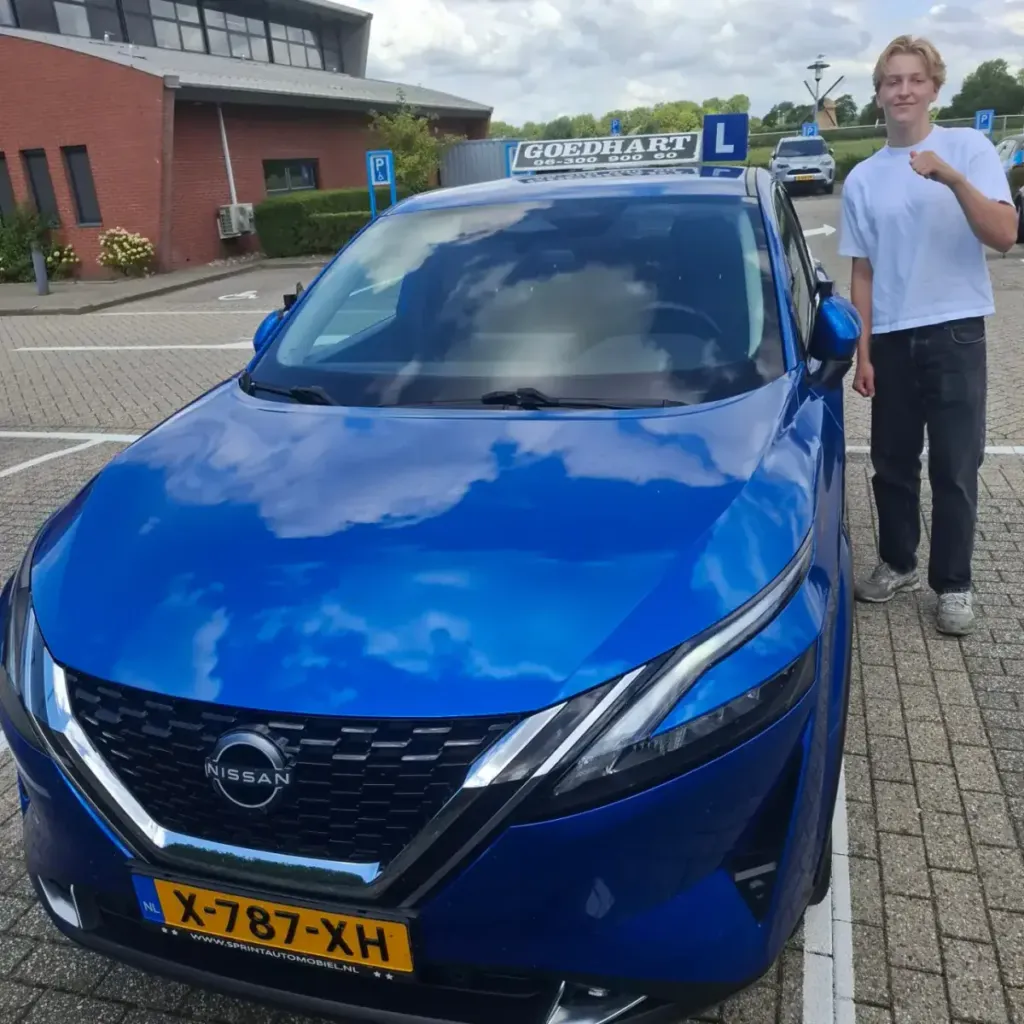Geslaagde leerling Jens bij de blauwe lesauto van Autorijschool Goedhart