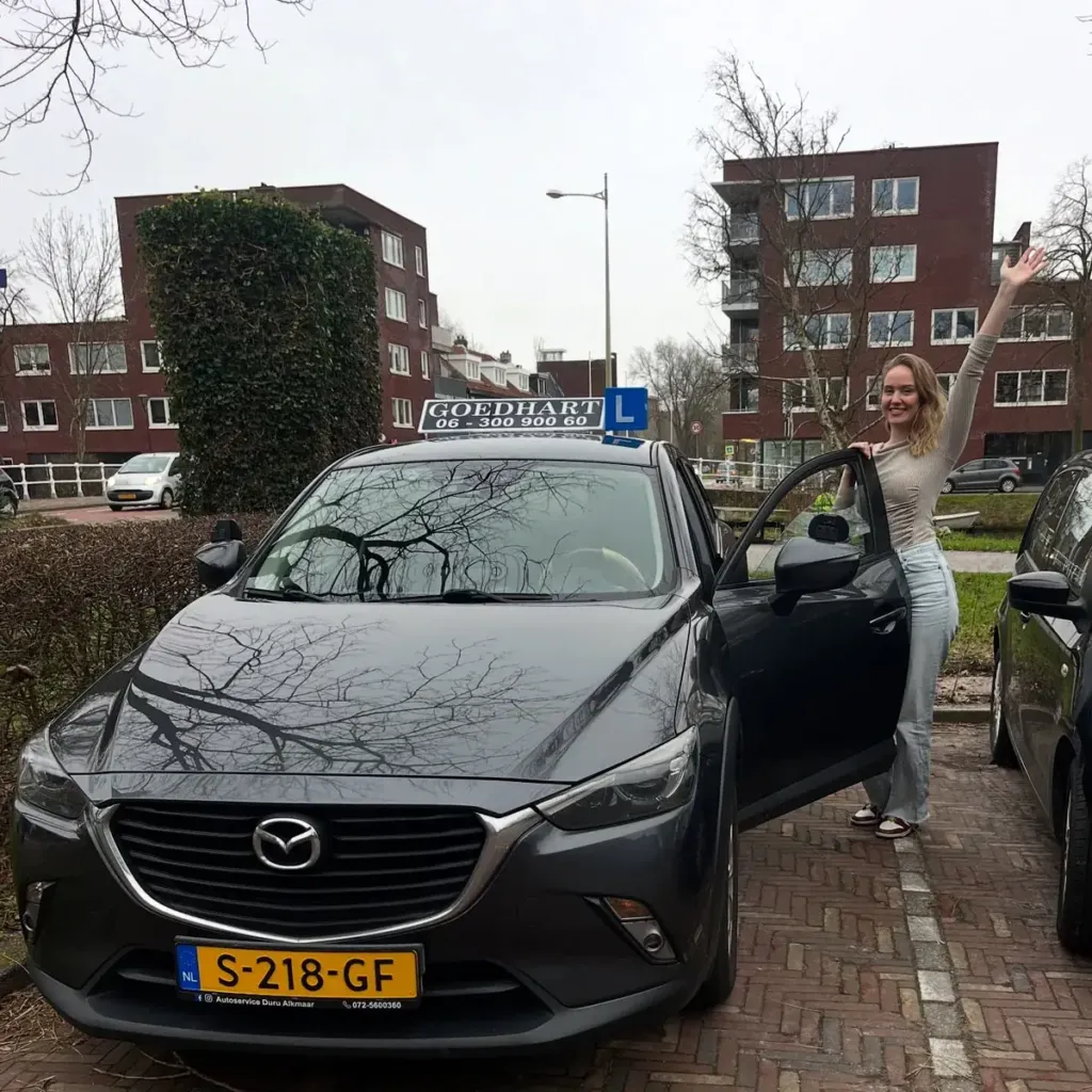 Geslaagde leerling Marit bij de grijze lesauto van Autorijschool Goedhart