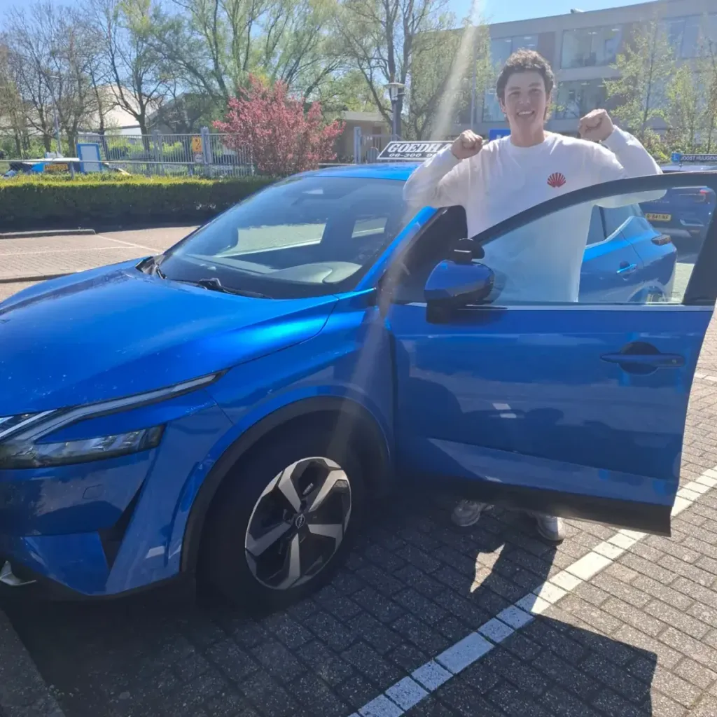 Geslaagde leerling Melle bij de blauwe lesauto van Autorijschool Goedhart