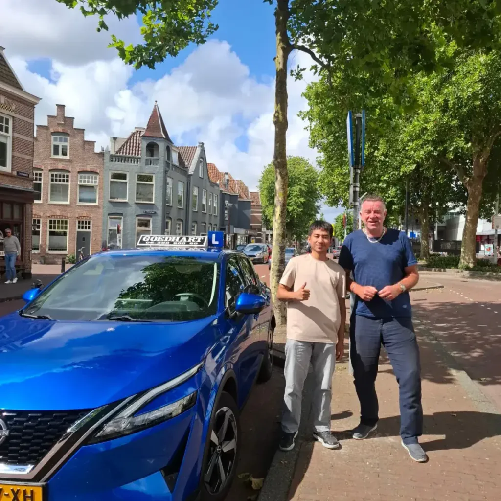Geslaagde leerling Roy bij de blauwe lesauto van Autorijschool Goedhart
