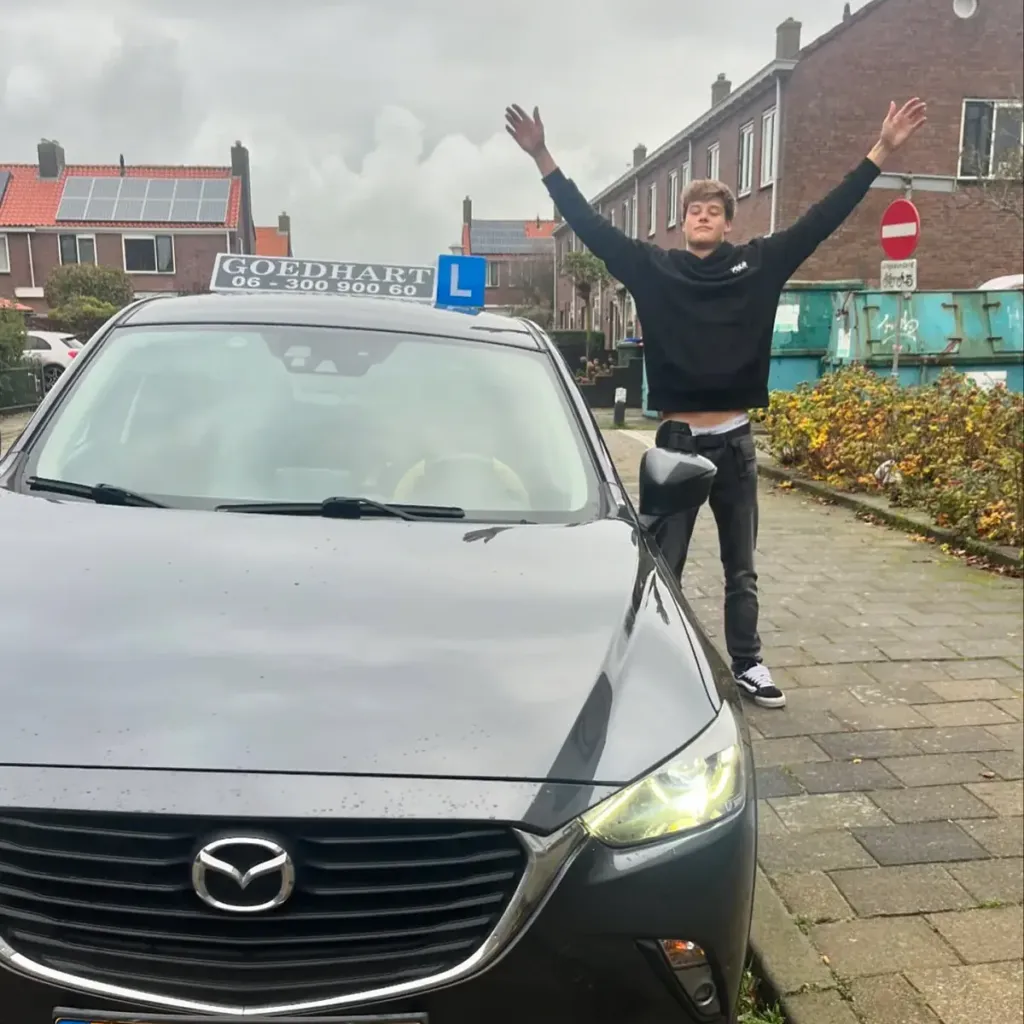 Geslaagde leerling Stijn bij de grijze lesauto van Autorijschool Goedhart